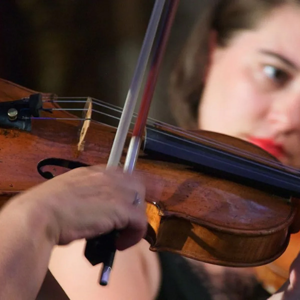 Closeup of two people playing the violin