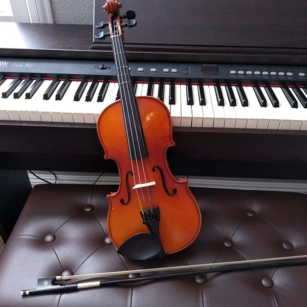 Violin and bow lying in front of a piano